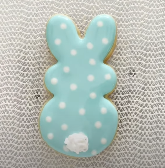 Image of a bunny sugar cookie decorated with blue royal icing and white dots.