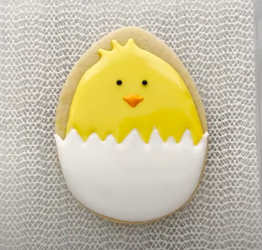 Image of an egg shaped cookie decorated to look like a hatching chick