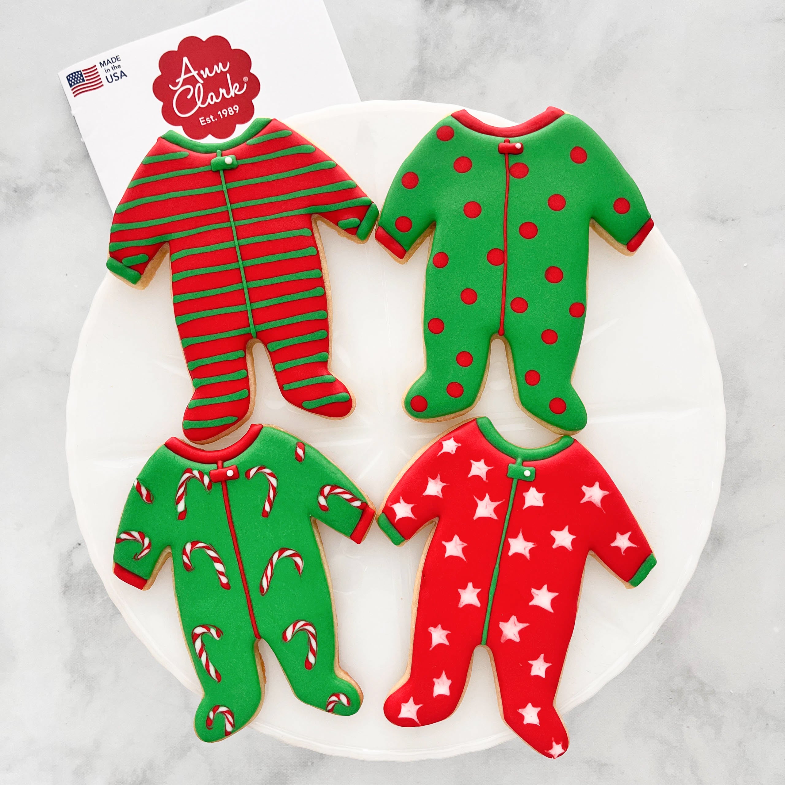 Four pajama-shaped sugar cookies decorated with red and green royal icing.