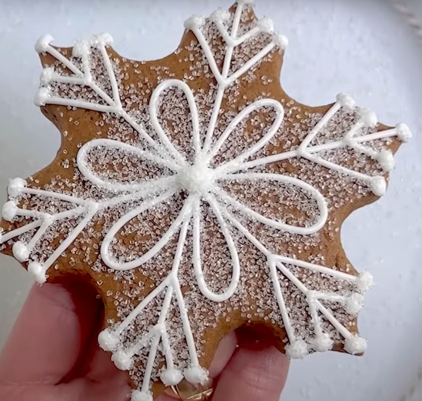 Gingerbread cookie in the shape of a snowflake, decorated with white royal icing