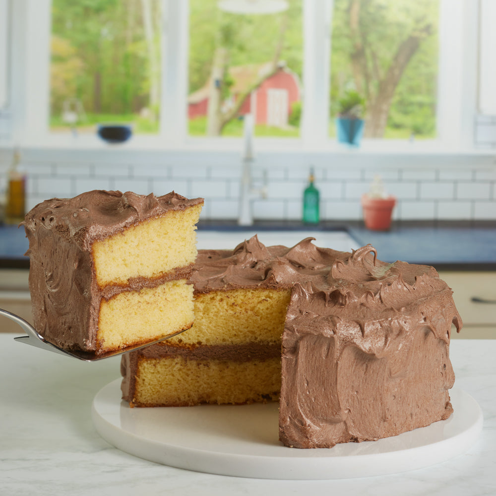 yellow cake with chocolate frosting with a slice being lifted on a spatula.