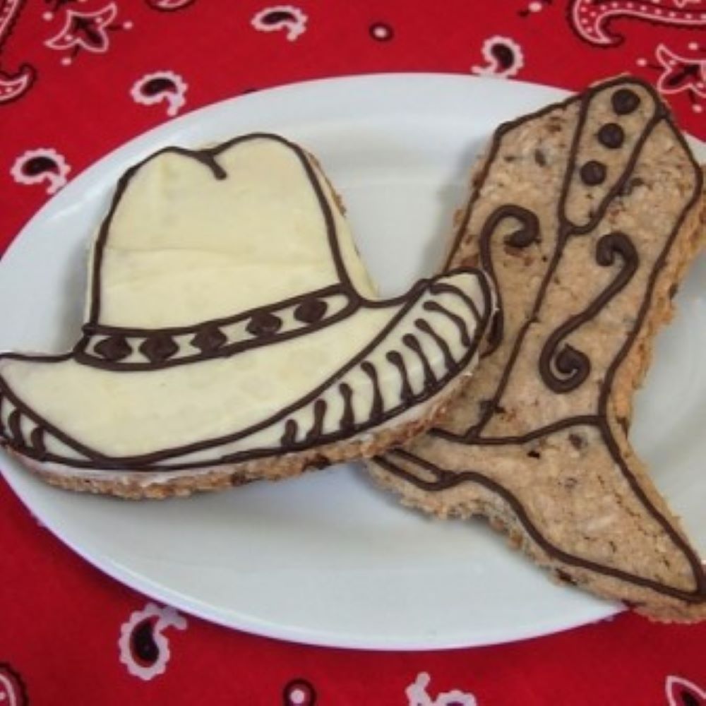 cowboy hat and cowboy boot shaped cookies decorated with royal icing on a white plate 