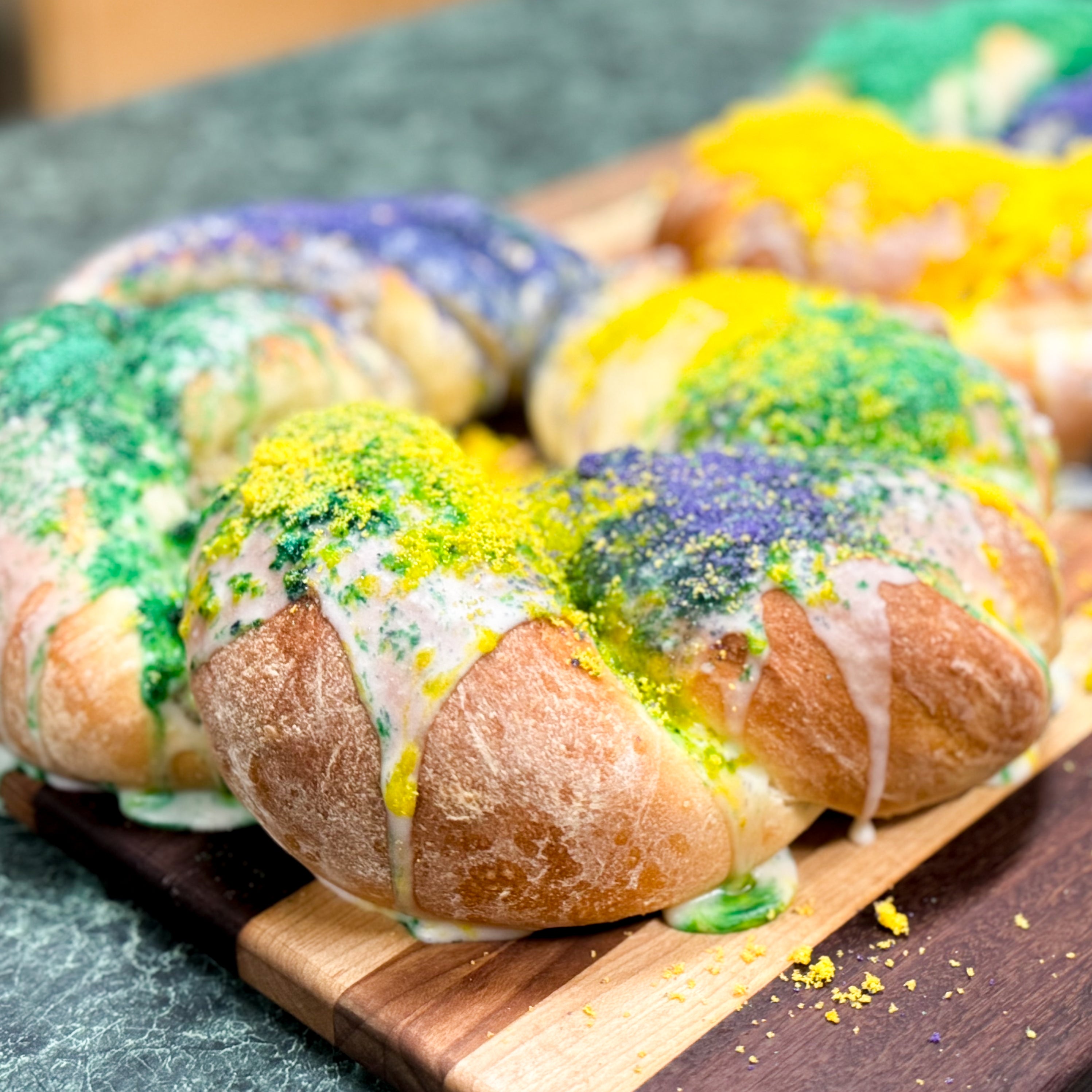king cake iced with yellow, purple, and green sugar