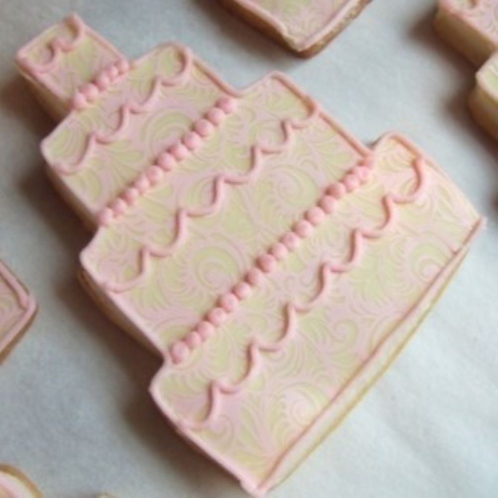 cake shaped cookie with light pink icing on parchment paper