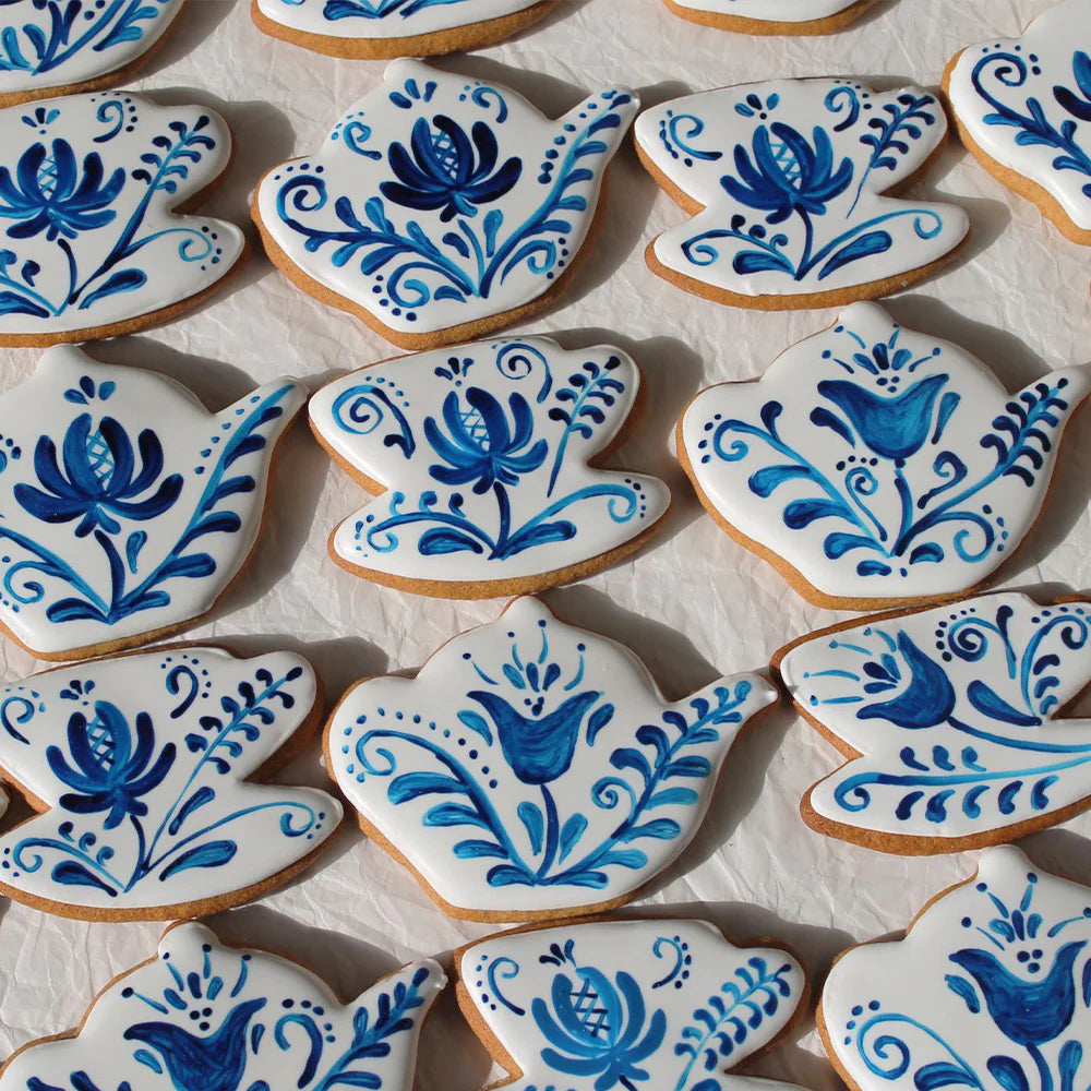 tea pot and tea cup shaped cookies with white icing and blue floral details on a white background