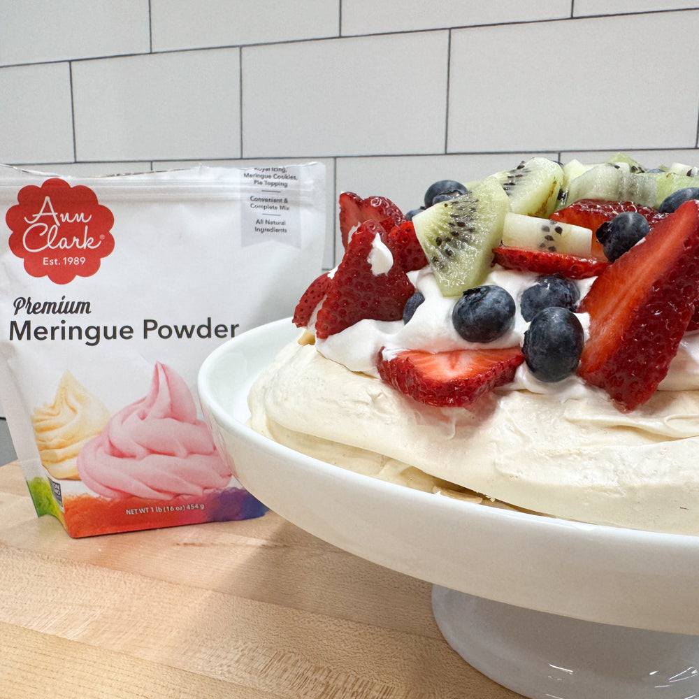 Image of a fruit-topped pavlova with Ann Clark Meringue Powder packaging in the background.
