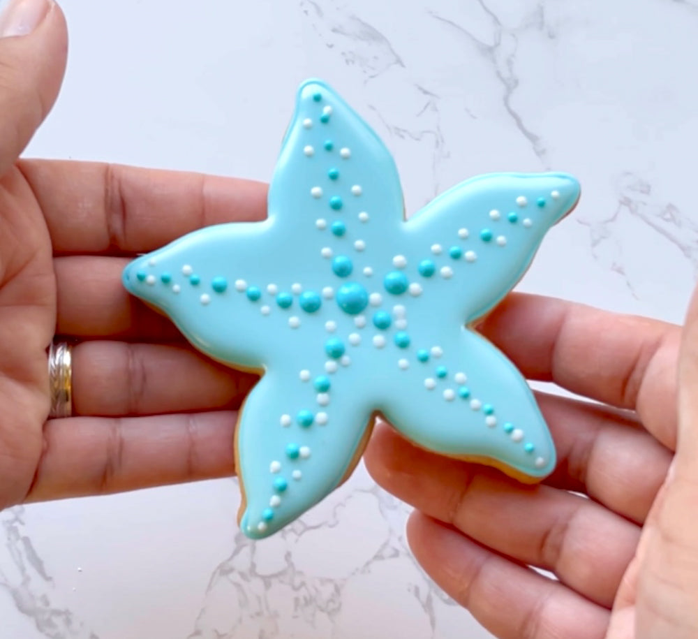 Hands holding a blue starfish cookie