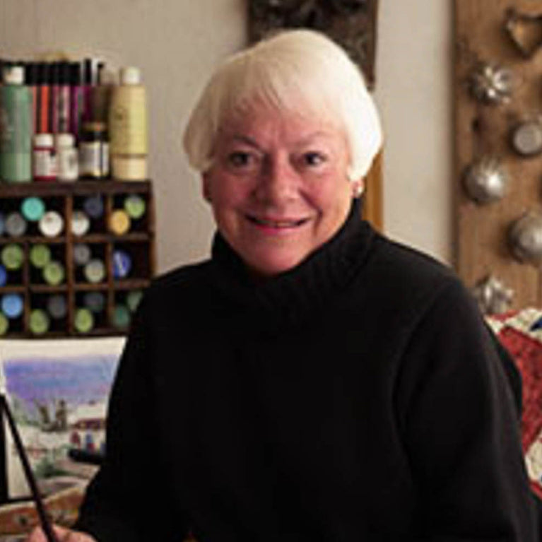 Ann Clark sitting at a desk with painting supplies