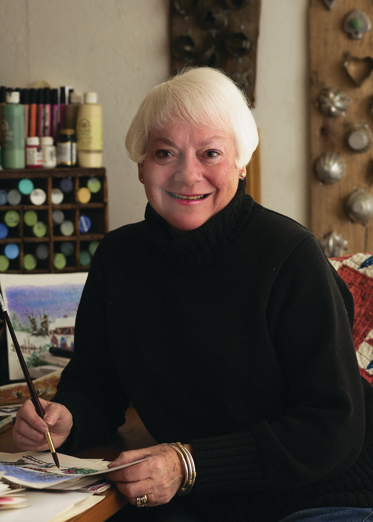 Ann Clark at her desk with painting supplies