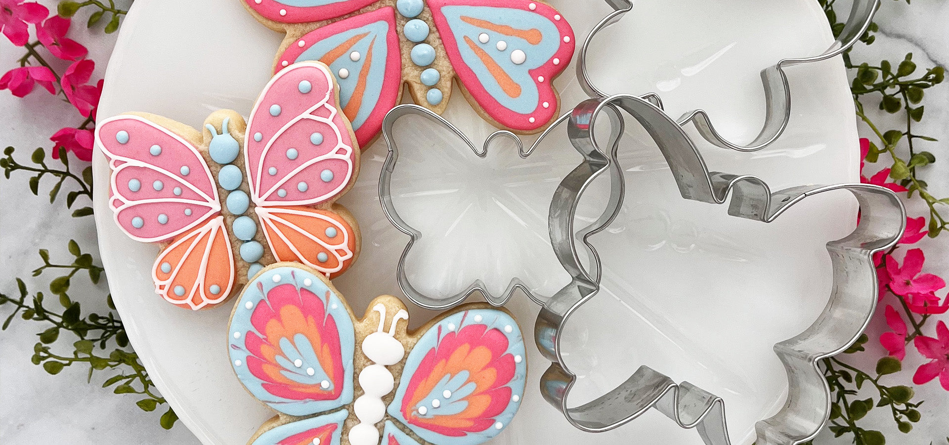 Butterfly cookies and cookie cutters on a white plate