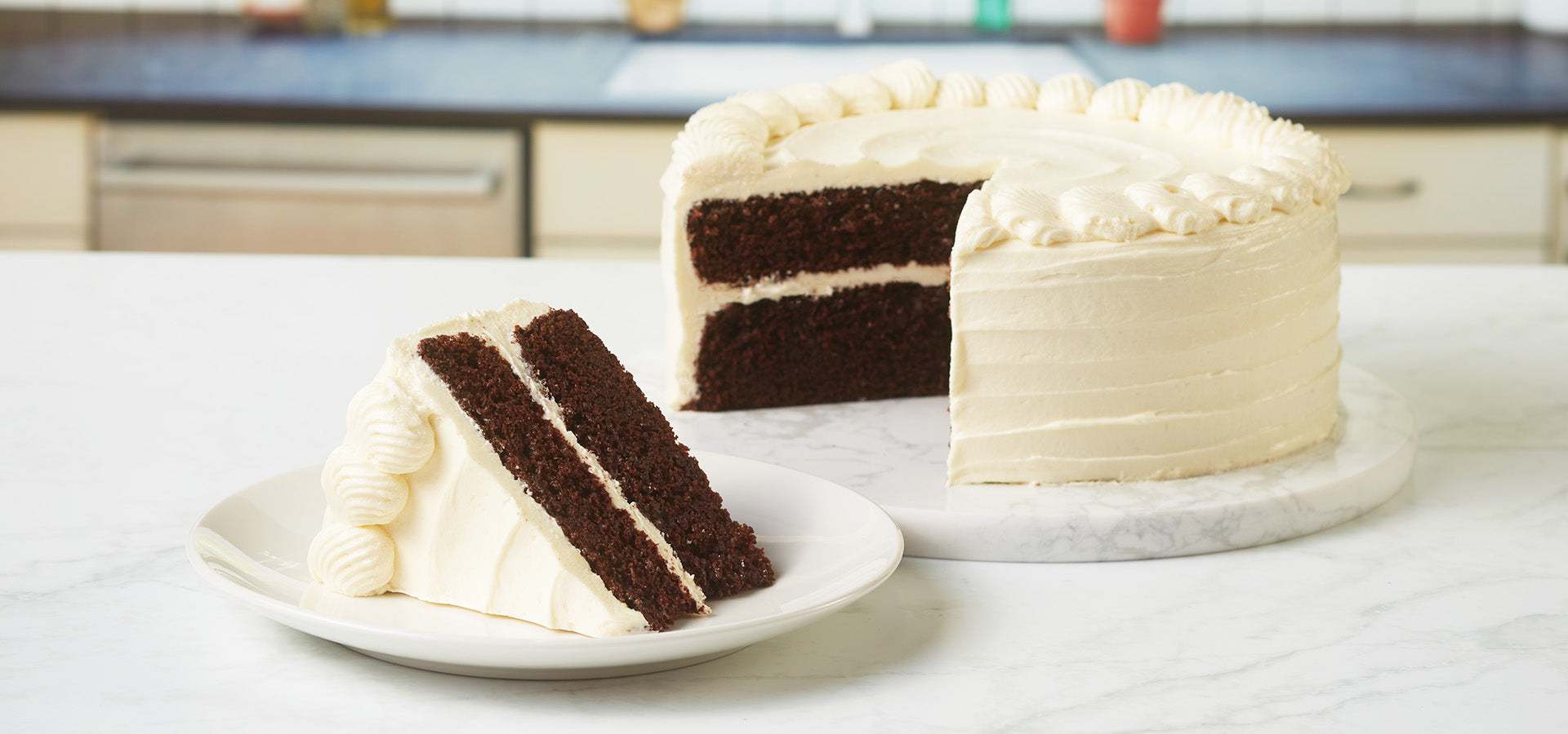 Chocolate cake with vanilla frosting. Slice of cake sitting in front of full cake.