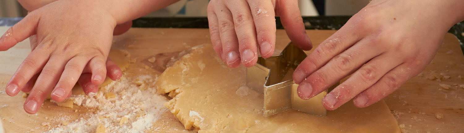 Children's hands making cookies with Ann Clark cookie cutters