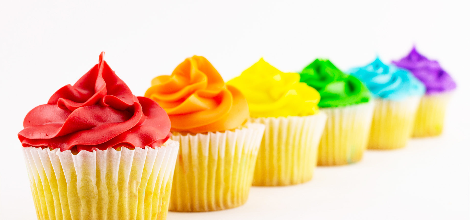 Line of colorful cupcakes frosted in the colors of the rainbow