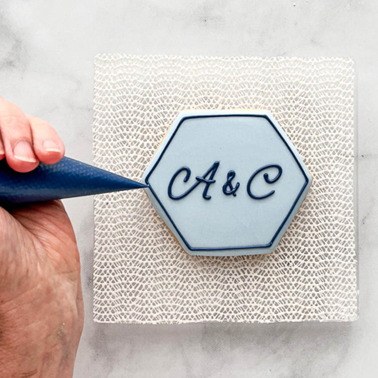 Decorating a hexagonal cookie with A & C written on the top
