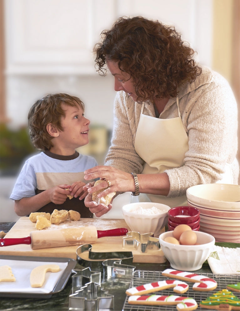 Mother and child smiling at each other as they prepare dough in the kitchen for cookies