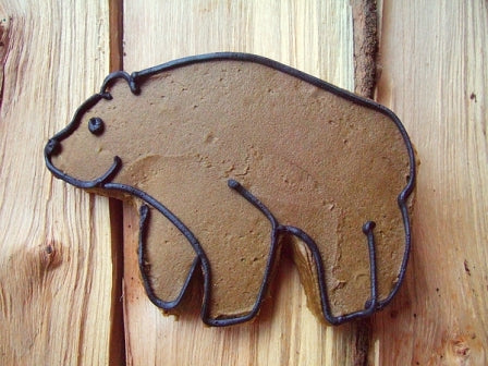 granola cookie shaped like a bear with brown and black icing on a wooden table