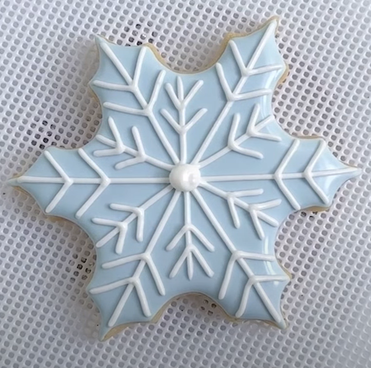 Snowflake shaped cookie decorated with blue and white royal icing.