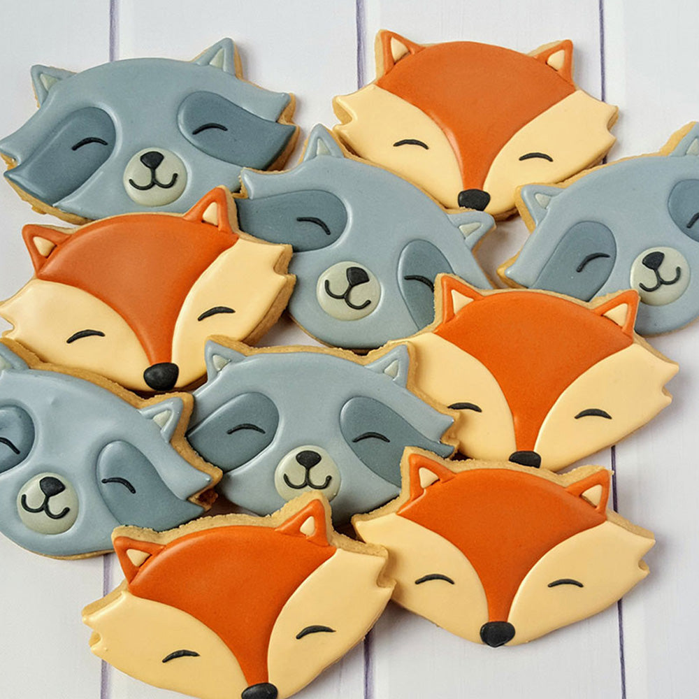 cute fox and racoon shaped cookies on a wooden backdrop