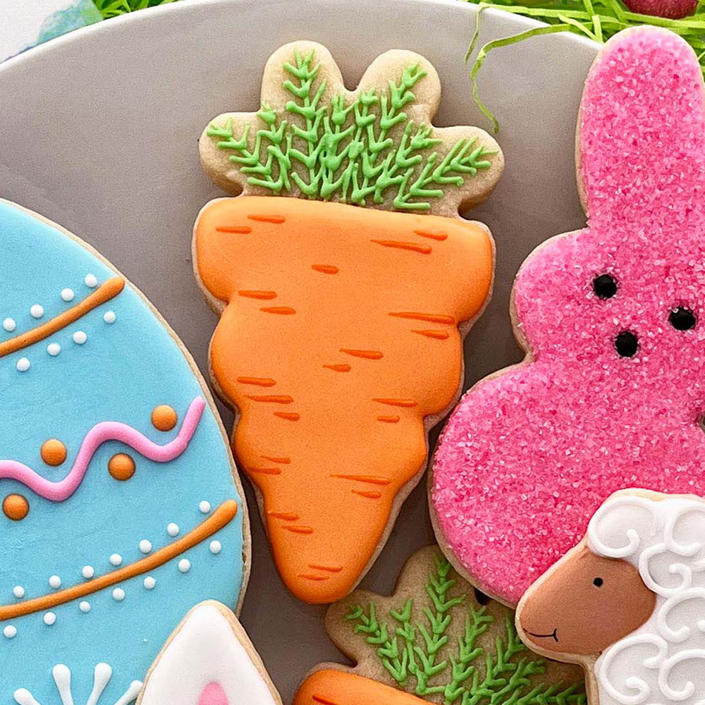 carrot shaped cookie along with easter shapes on a plate