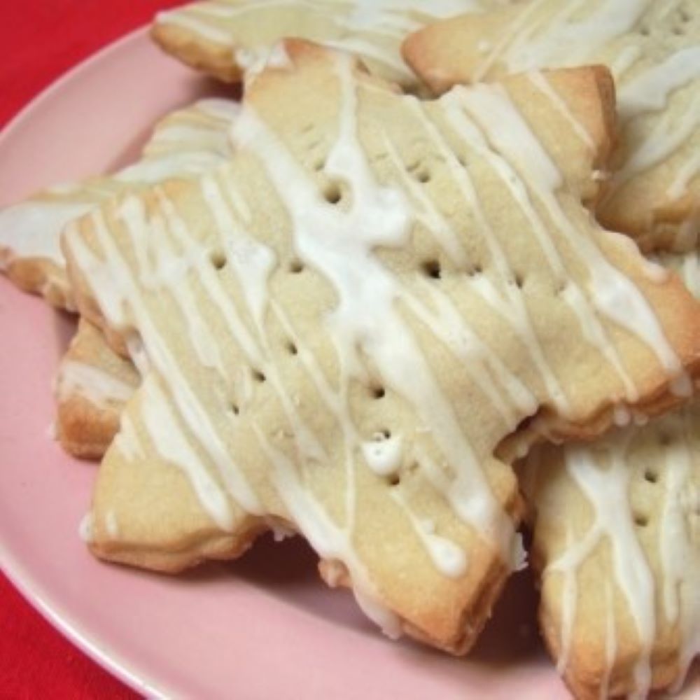 cranberry tart shaped like a snowflake and drizzled with a glaze on a light pink plate