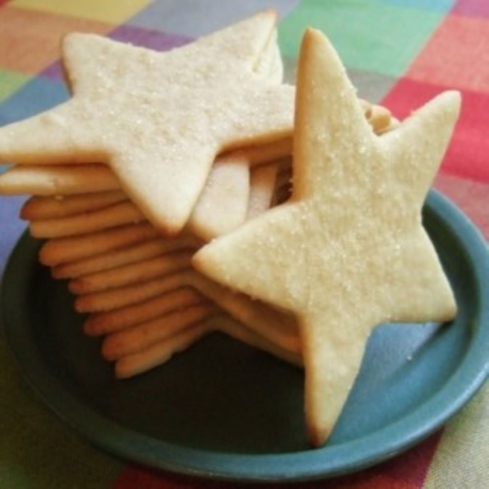 lemon sugar cookies in the shape of a star piled on a blue plate