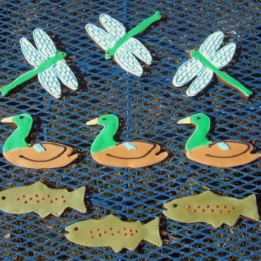 dragonfly, duck, and fish shaped cookies on a metal picnic table