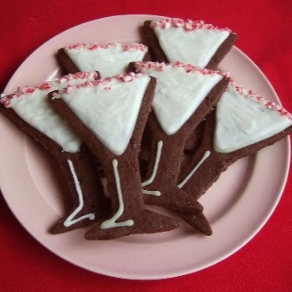 martini shaped cookies decorated with white royal icing and crushed peppermint on a light pink plate