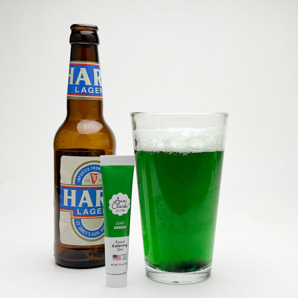Glass of green beer with food coloring gel and beer bottle
