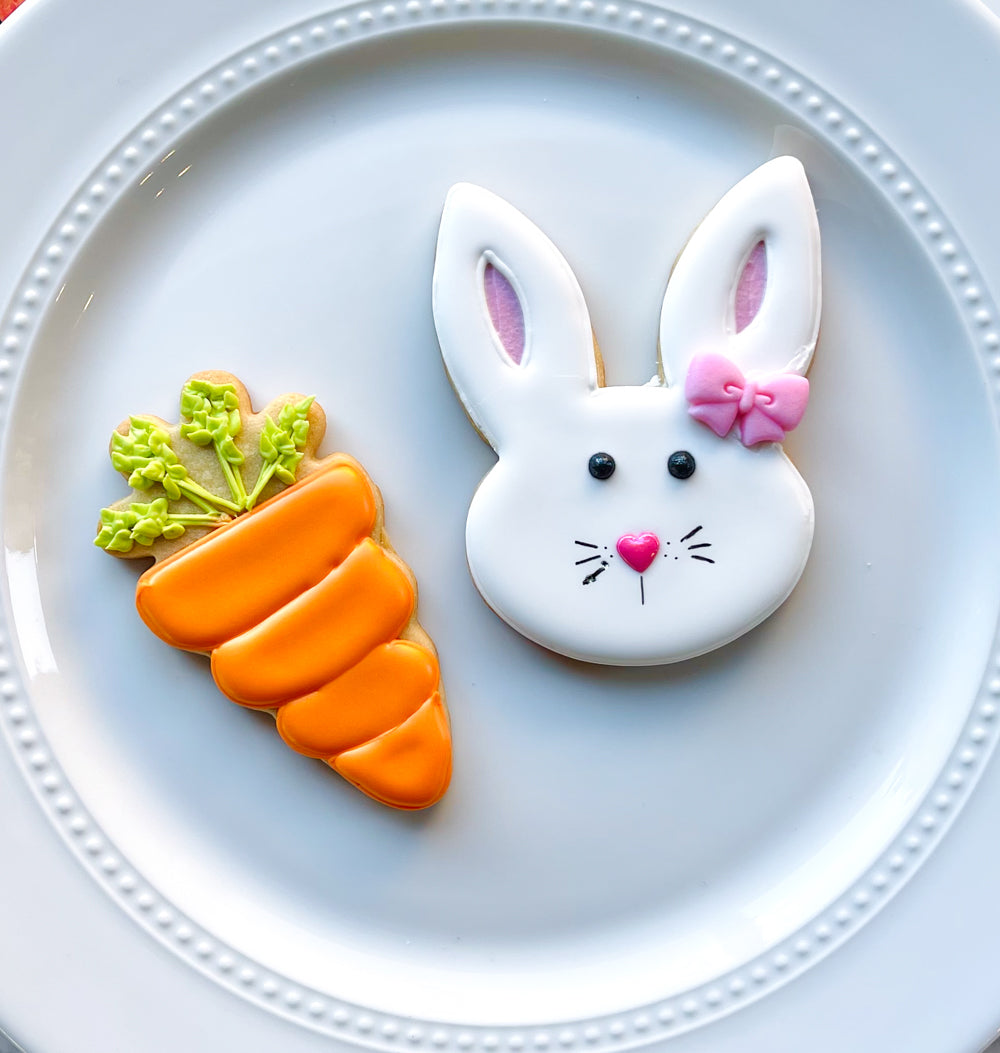 Image of an Easter Bunny sugar cookie and a carrot sugar cookie on a white plate.