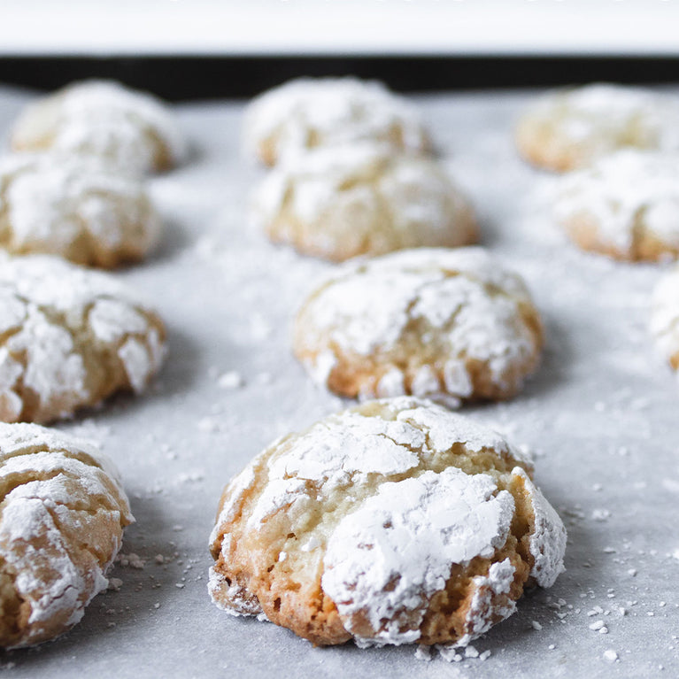 Cookies dusted with powdered sugar on a sheet of parchment paper