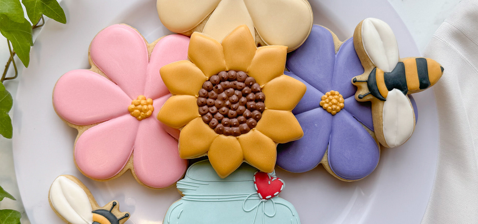 Flower, bee, and jar cookies on a white plate