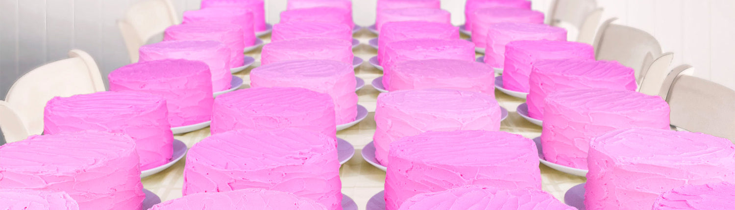 Rows of pink frosted cakes on a  white table