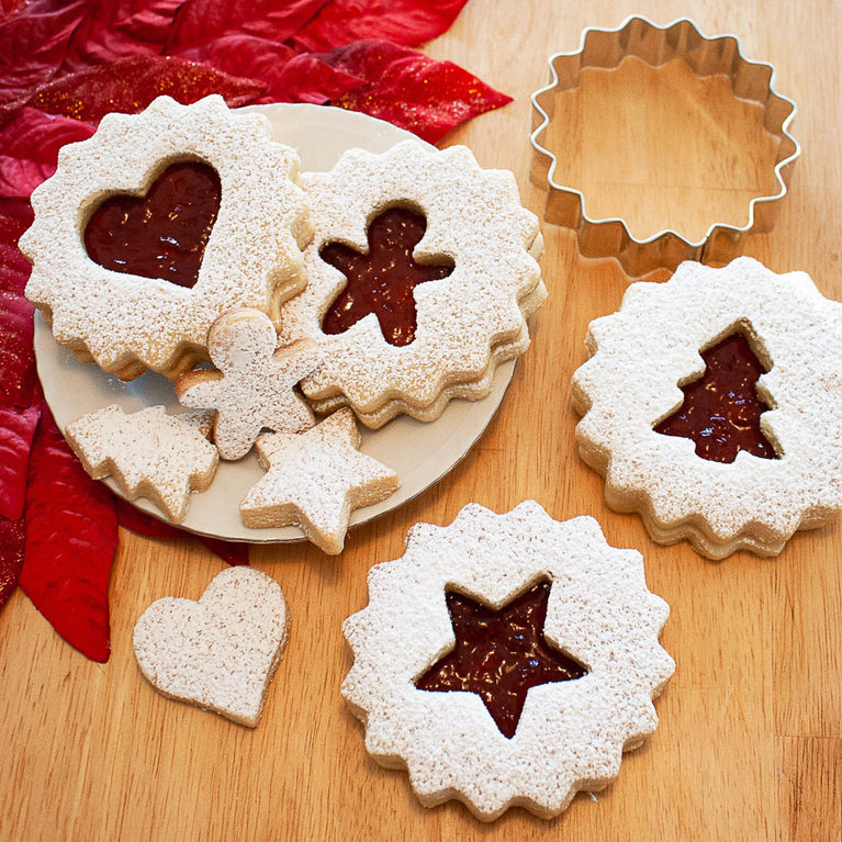Linzer cookies on a wooden table top with cookie cutter
